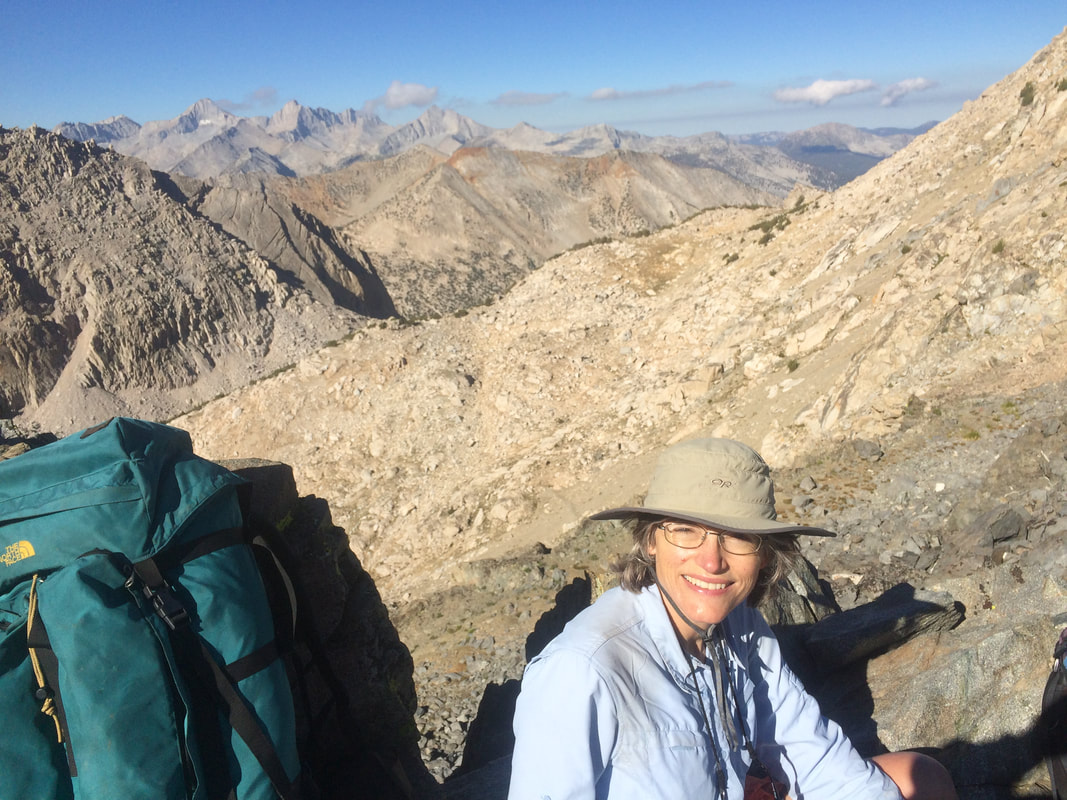 Bernadette Powell sits next to her backpack on a high Sierra pass