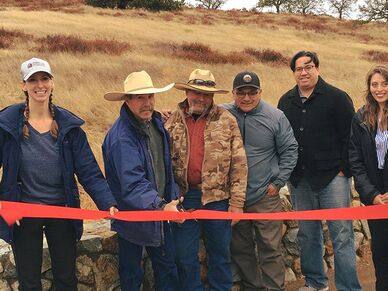 A group of people stands ready to cut the ribbon on the Bacon Ranch Homestead at Pinnacles National Park