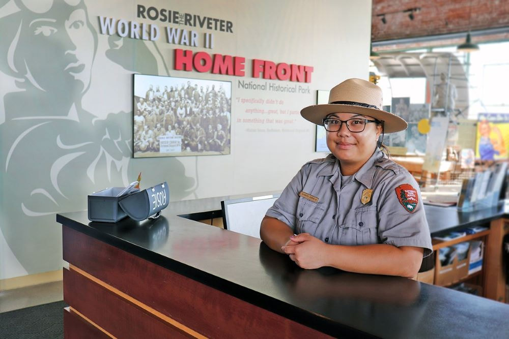 A National Park Service ranger stands at the visitor center desk of Rosie the Riveter World War II Home Front National Historical Park